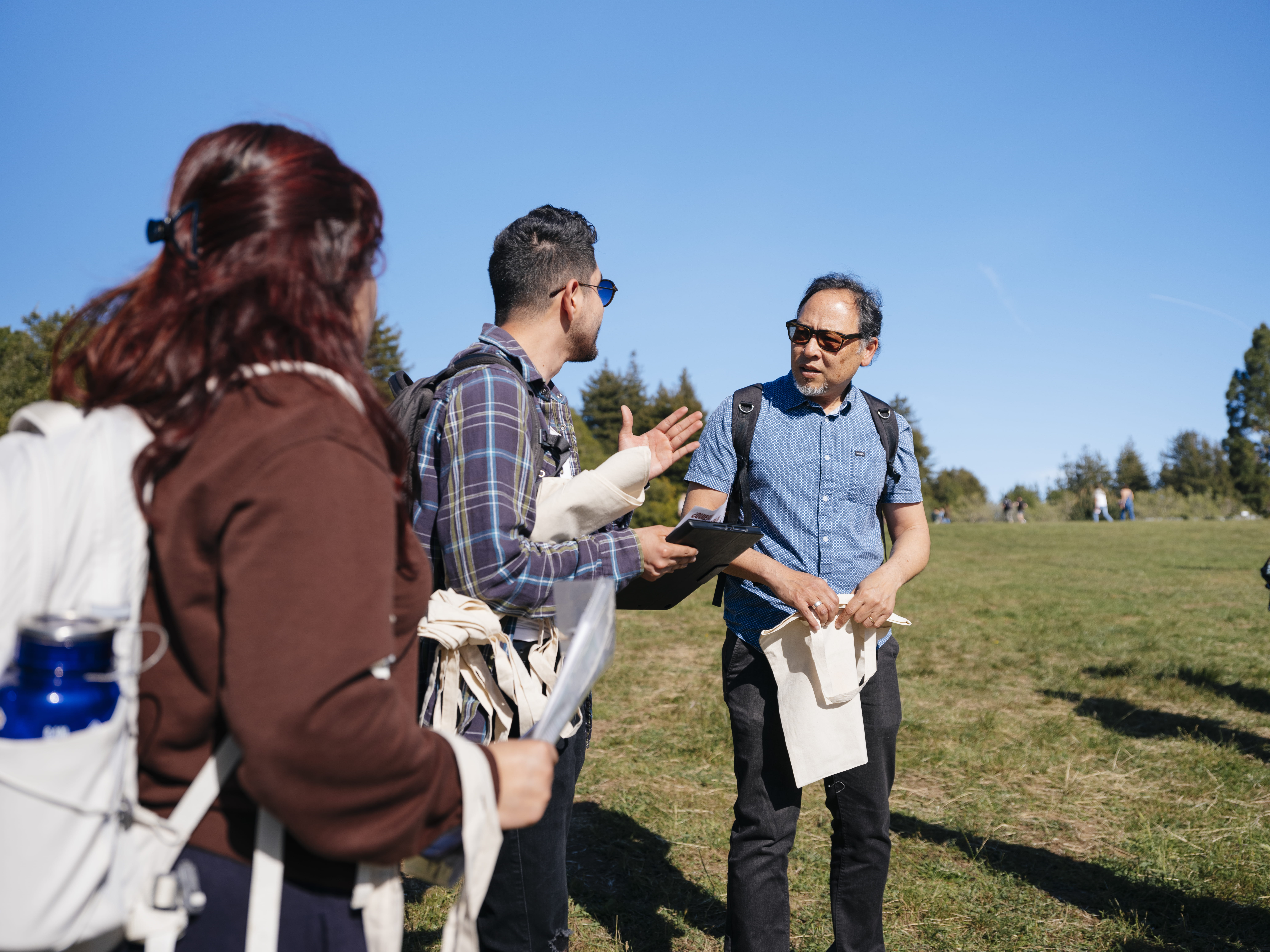 two students talking to a faculty member in an outdoor setting